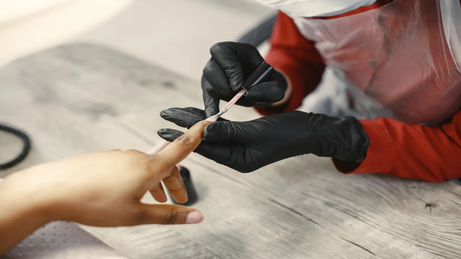 Profesional aplicando esmalte semipermanente sobre una uña en una mesa de manicura