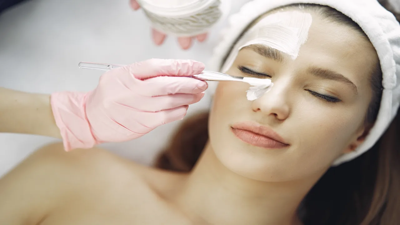 Profesional aplicando una mascarilla durante una limpieza facial en cabina