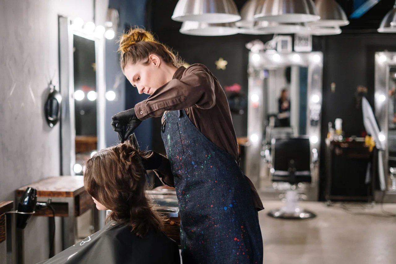 Profesional aplicando color en el cabello de una clienta en salón