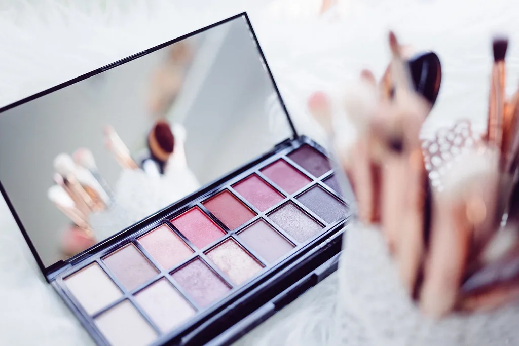 Paleta de sombras y brochas de maquillaje en tonos suaves